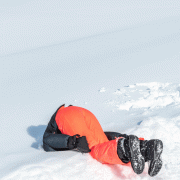 Mann im Schnee, orange Skihose