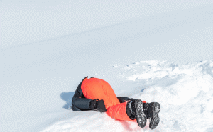 Mann im Schnee, orange Skihose
