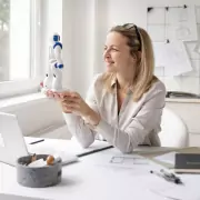 Darstellung einer Frau im Home Office mit einem Roboter