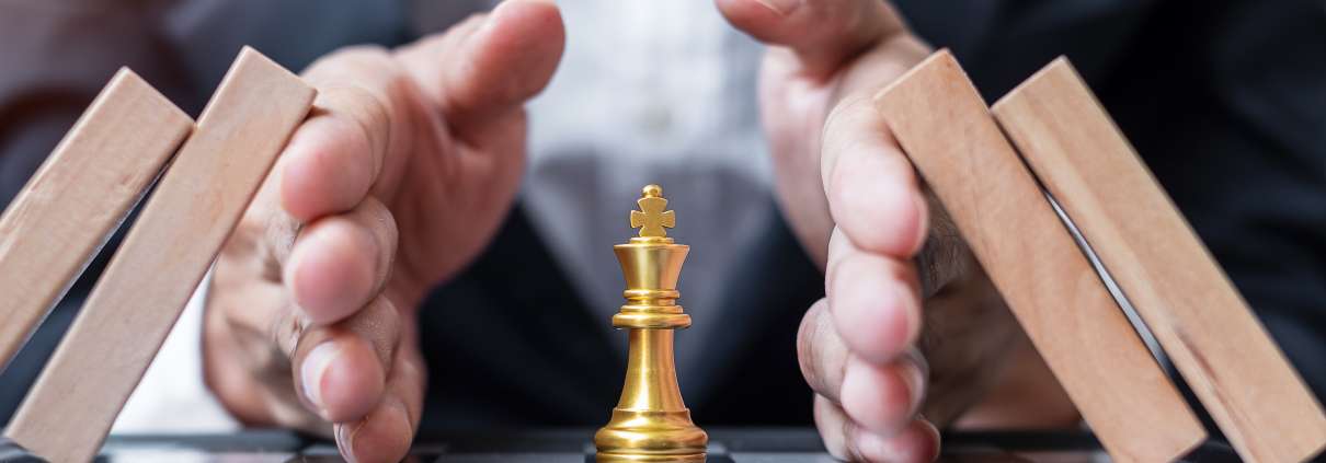 Hände schützen eine Schachfigur. Symbolisiert Risikomanagement.