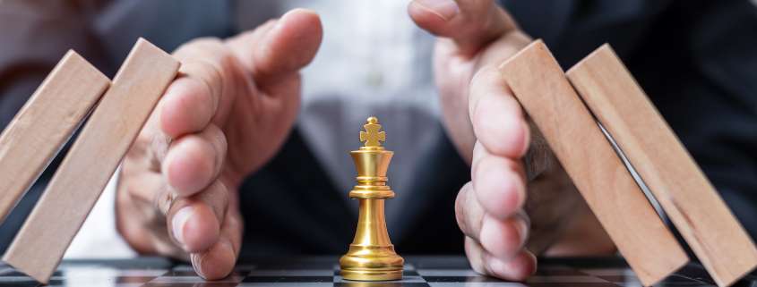 Hände schützen eine Schachfigur. Symbolisiert Risikomanagement.
